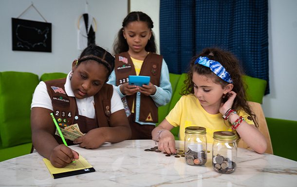 Three Girl Scouts counting change.