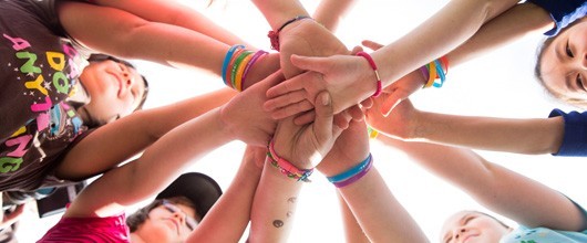 ways-to-participate-hero girls standing in circle with hands piled into the center