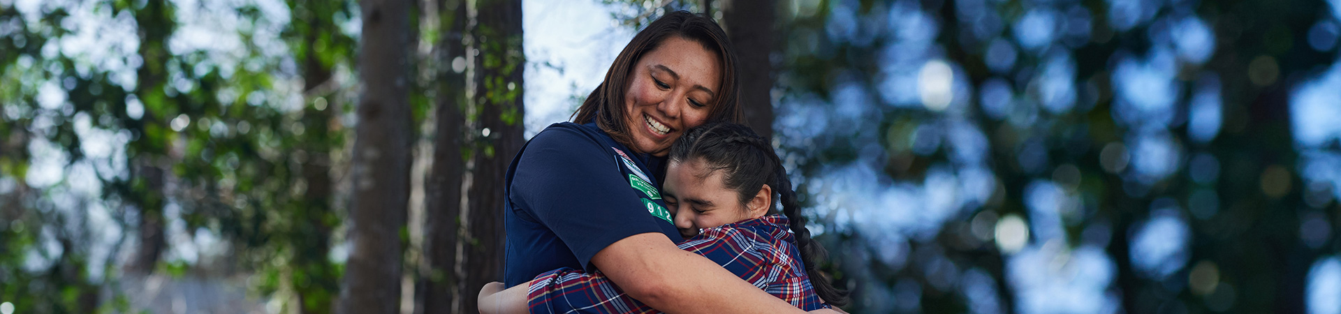  Adult volunteer hugging a tween Girl Scout. Both are smiling. 