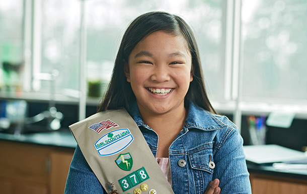 Portrait of an older Girl Scout in her sash smiling at the camera in a classroom
