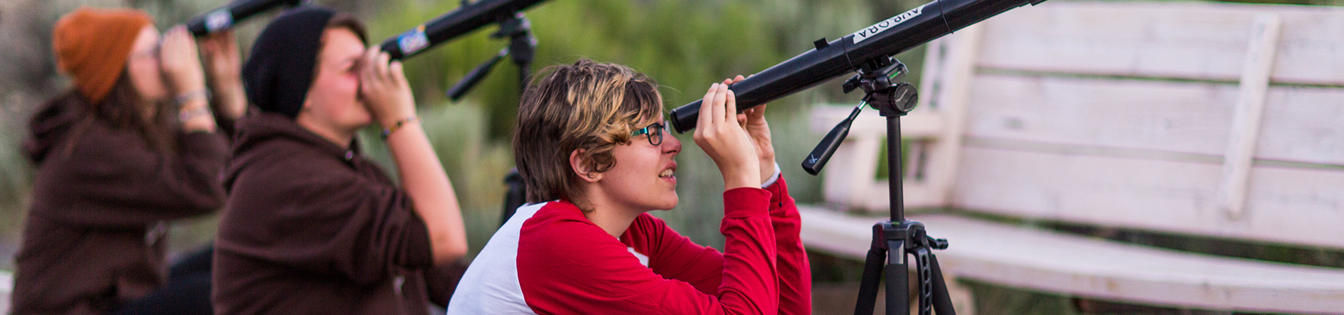  Teenage Girl Scout looking through a personal telescope at the daytime sky. 