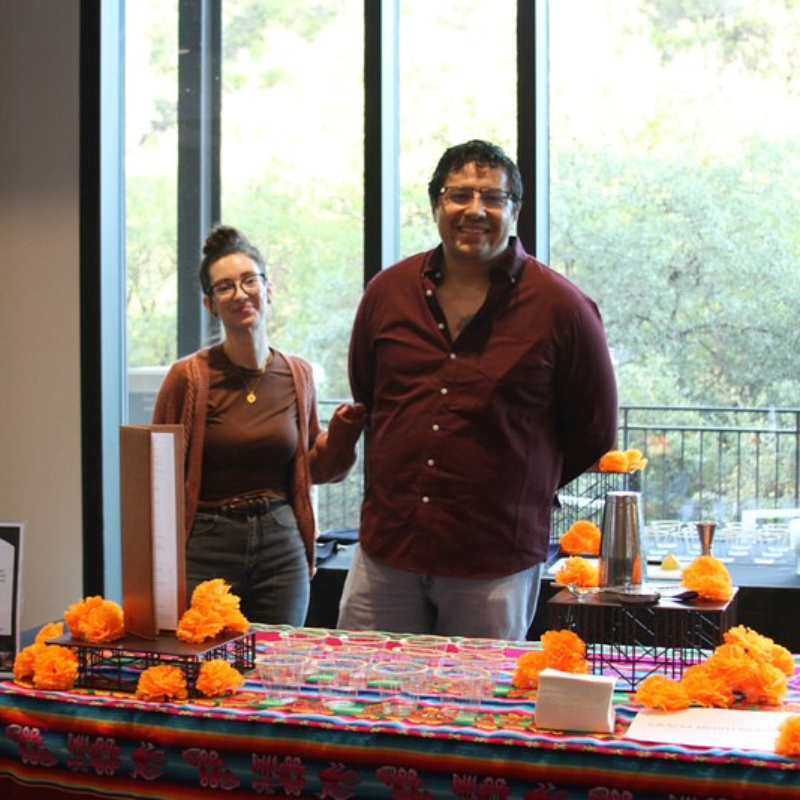 Man and woman smiling behind a drink table