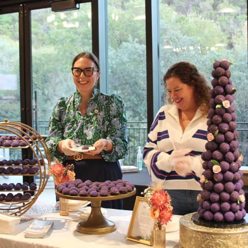 Smiling women in front of pastries