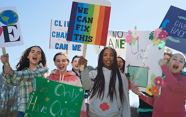 Group of girls participating in a march with signs reading "We can fix this".