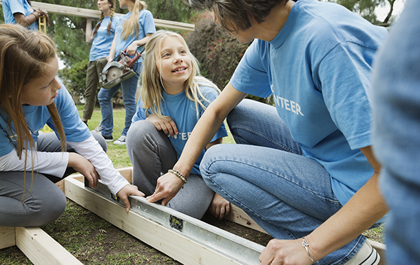 Volunteer assisting younger girls with a building project.